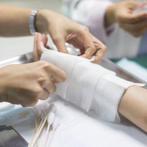 dokter brengt verband aan op arm van patient