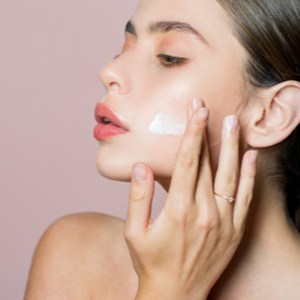 une femme met de la crème sur son visage