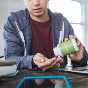 Sérieux jeune homme assis à la table en prenant de la vitamine D