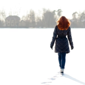 Jolie fille aux cheveux roux marchant sur un lac gelé et faisant un sentier