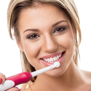 femme avec une brosse à dents électrique